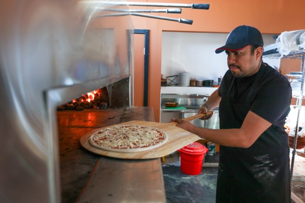 Milan Coal Fired Pizza & Grill co-owner Jorge Fuentes prepares a pizza on Thursday, Dec. 18, 2025. (JASON ARDAN / STAFF PHOTOGRAPHER)