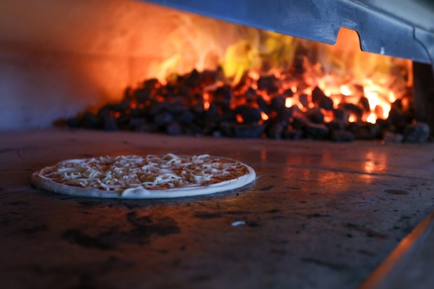 A pizza heats up at Milan Coal Fired Pizza & Grill on Thursday, Dec. 18, 2025. (JASON ARDAN / STAFF PHOTOGRAPHER)