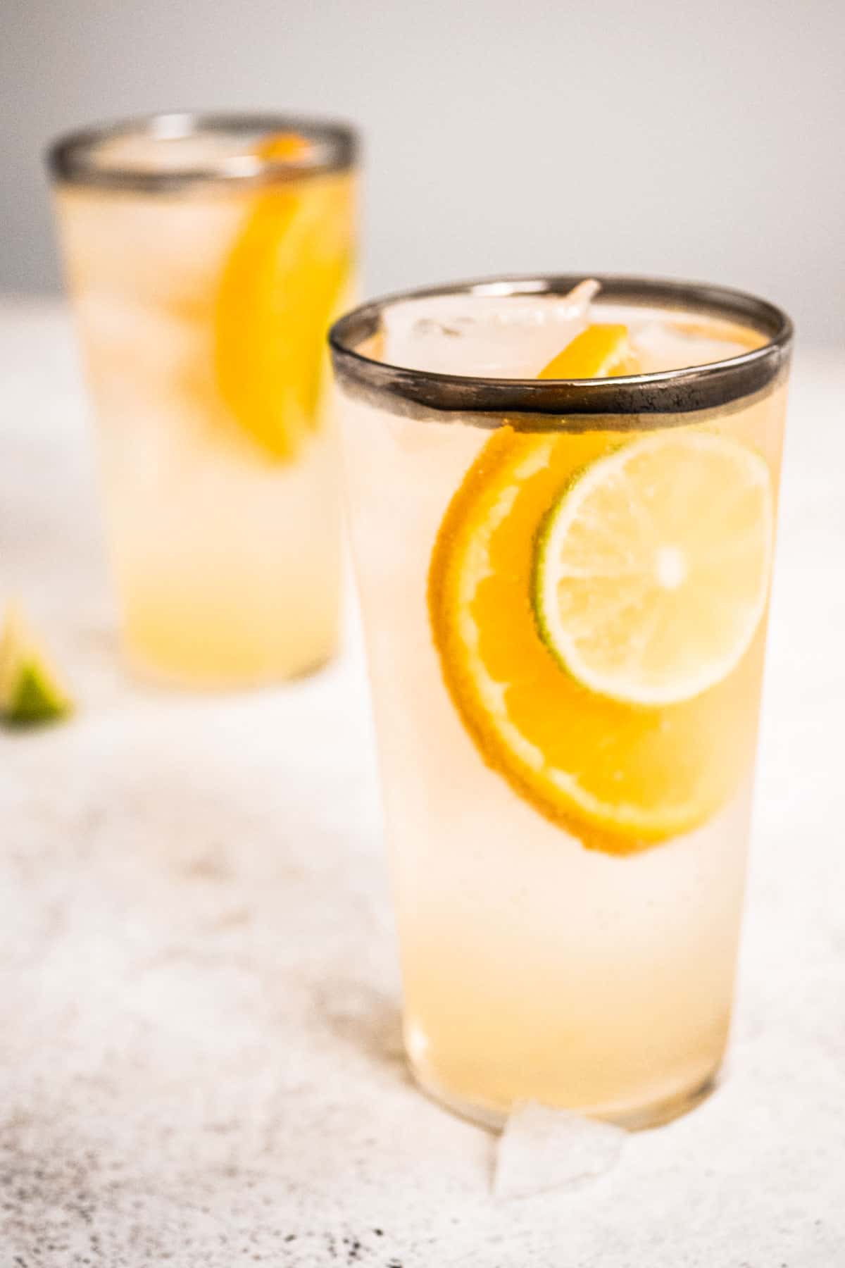 The Eternal Sunshine gin cocktail in a tall glass with an orange and lime slice floating near the top.