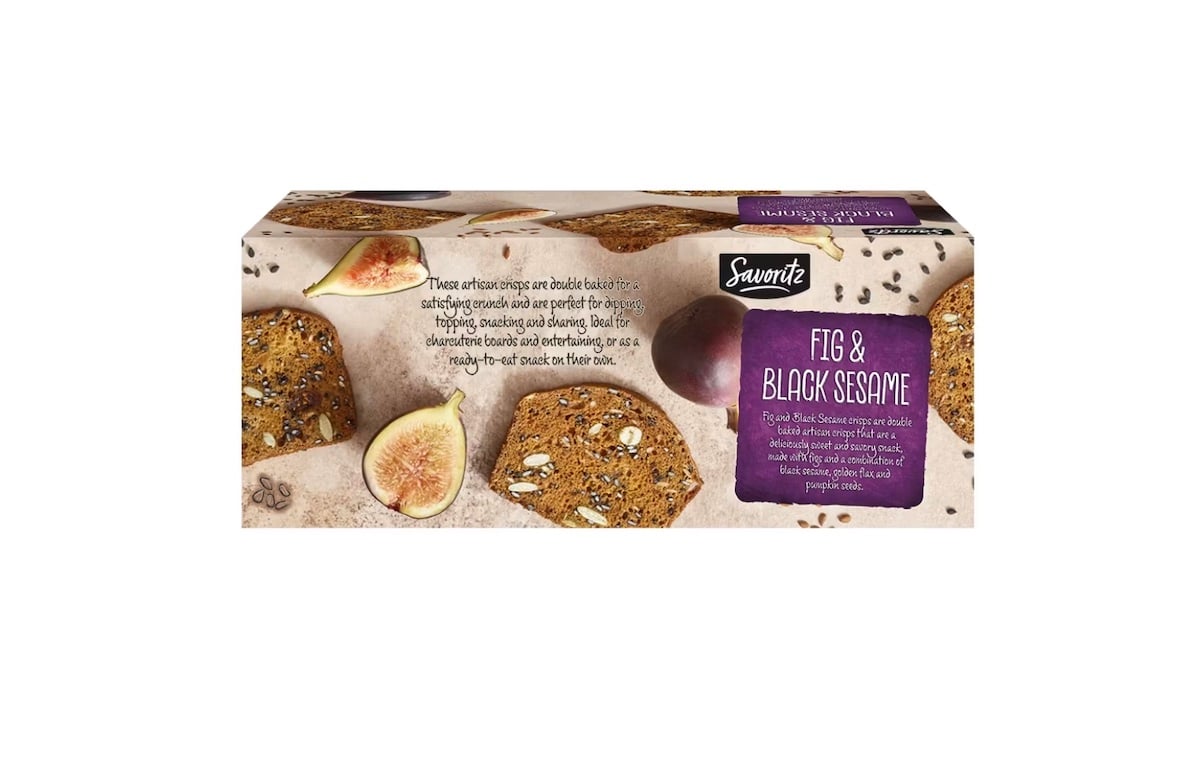 Rectangular box of Savour fig & black sesame crackers, featuring images of figs, crackers with seeds, and sesame seeds on the packaging. The label describes the product and ingredients in purple and white text.