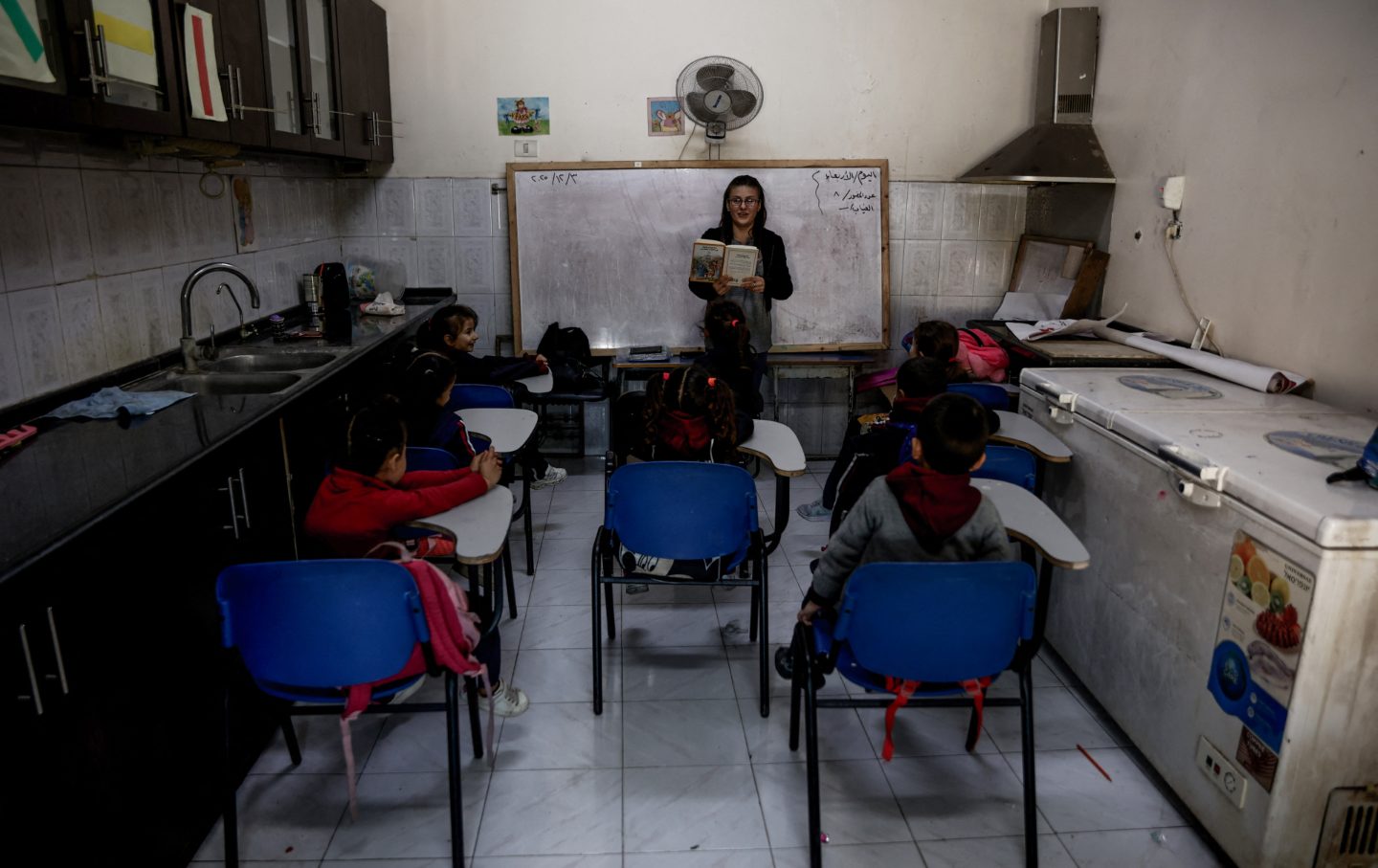Young learners listen to an educator during the start of classes at Latin Patriarchate School inside the Holy Family Catholic Church compound sheltering displaced Palestinians in Gaza City, on December 3, 2025.