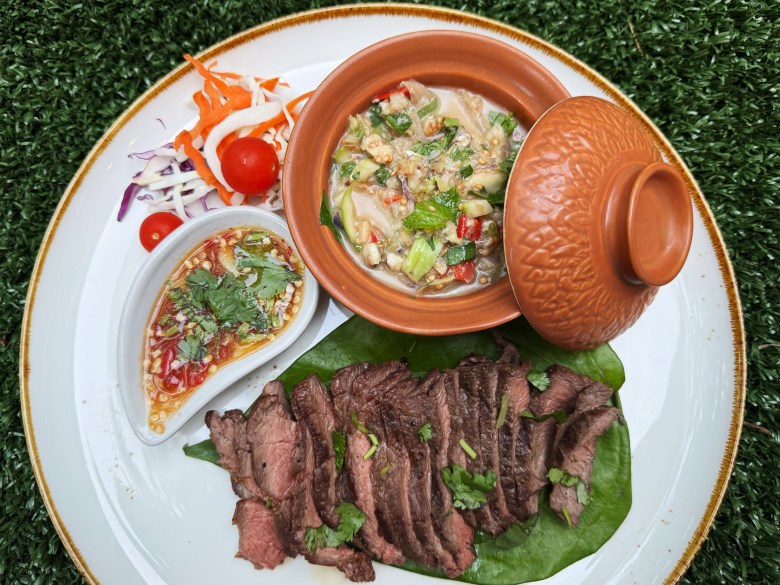 A platter of sliced grilled steak with dishes of Cambodian and Lao dipping sauces from Naga Bistro in Chamblee GA