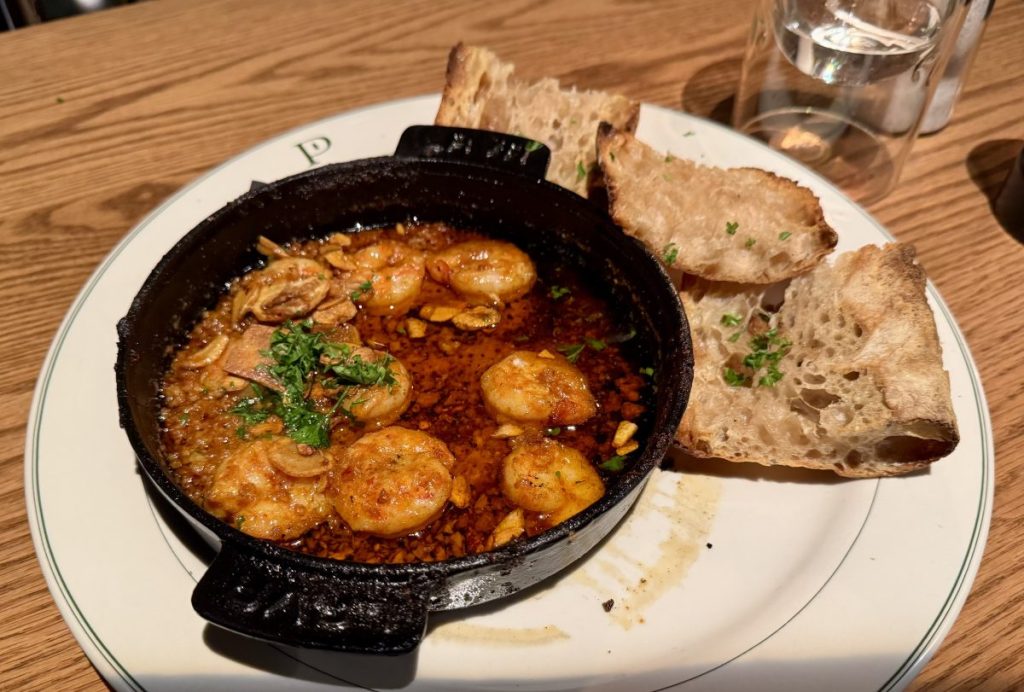 A cast iron plate with shrimp served with crusty bread