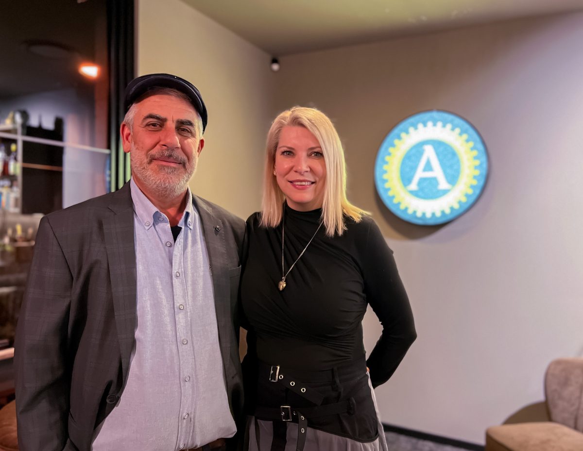 Sukru Kocak and Rania Vereschildt-Kocak stand in front of Anatolia logo