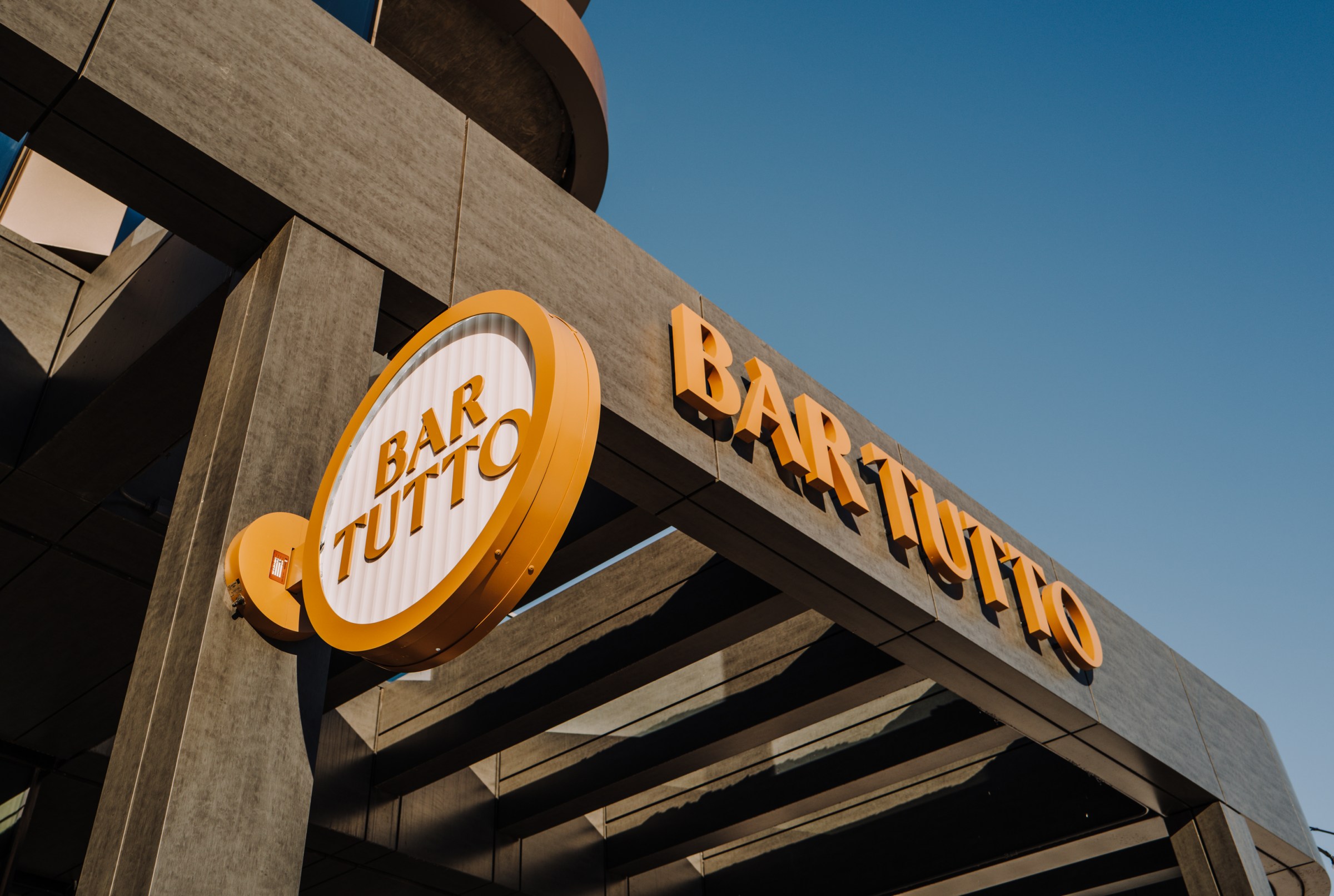 A sign and lettering that say “Bar Tutto” on the exterior of the restaurant.