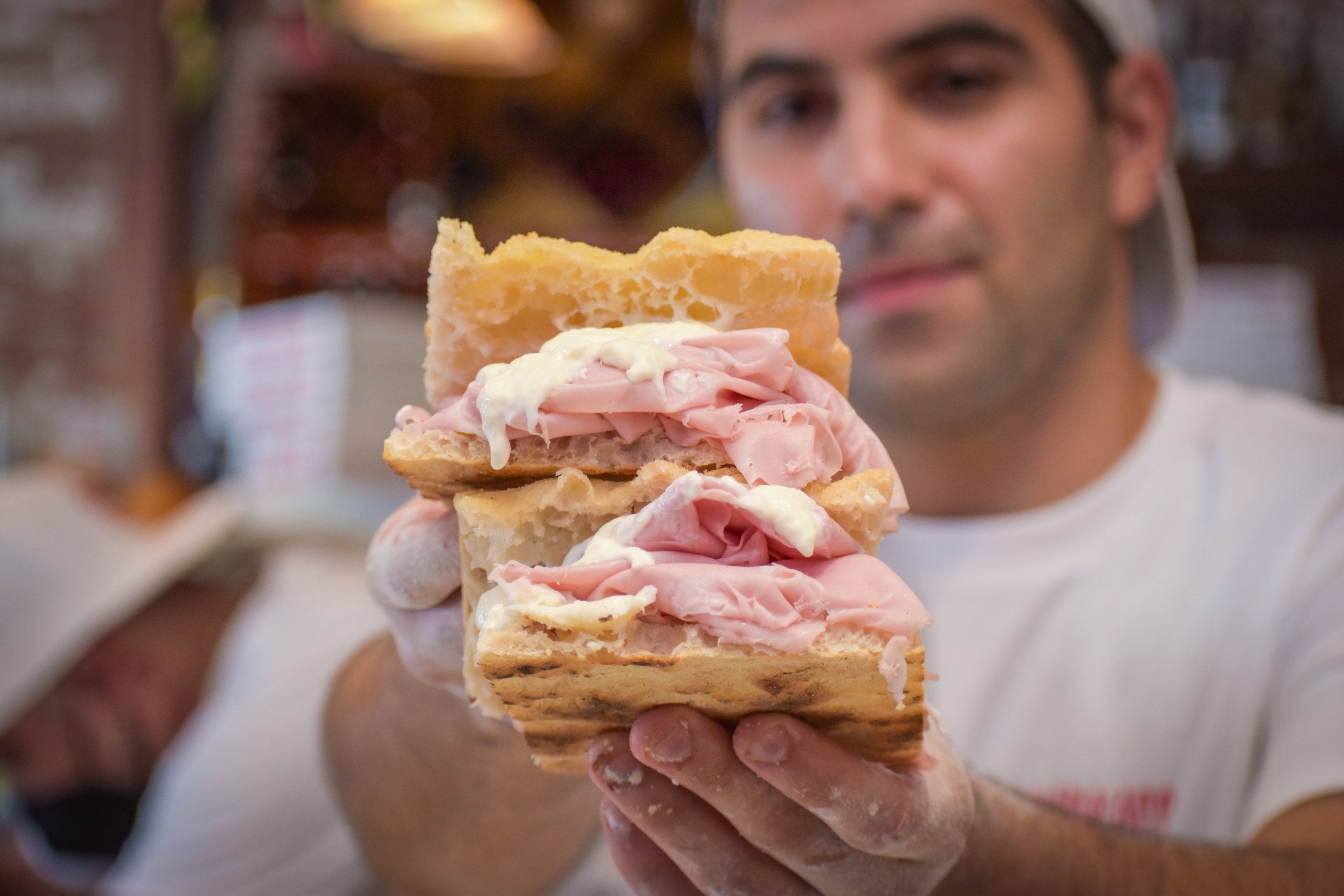 A man holds up a mortadella sandwich on house-made focaccia at La Parolaccia.