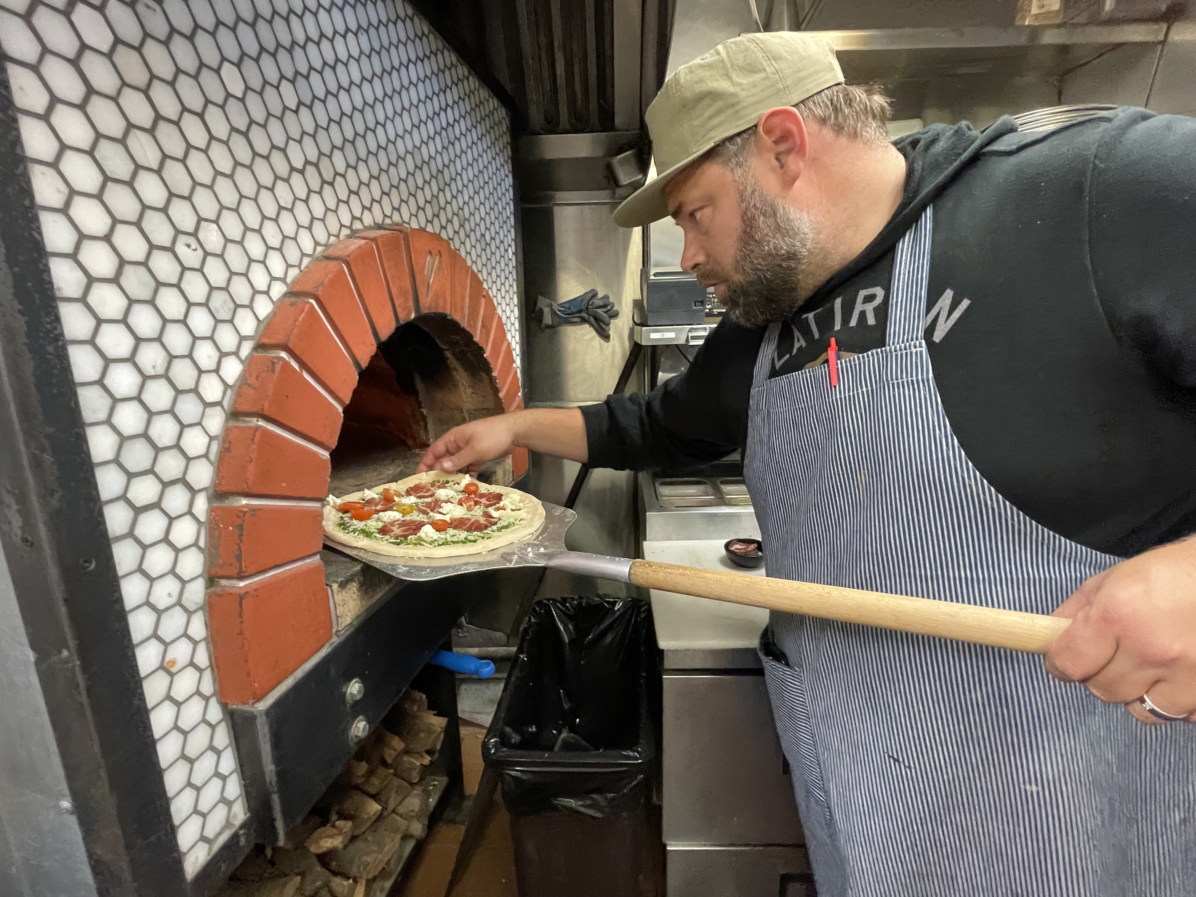 State Room owner Alex Stricker puts a pizza in the...