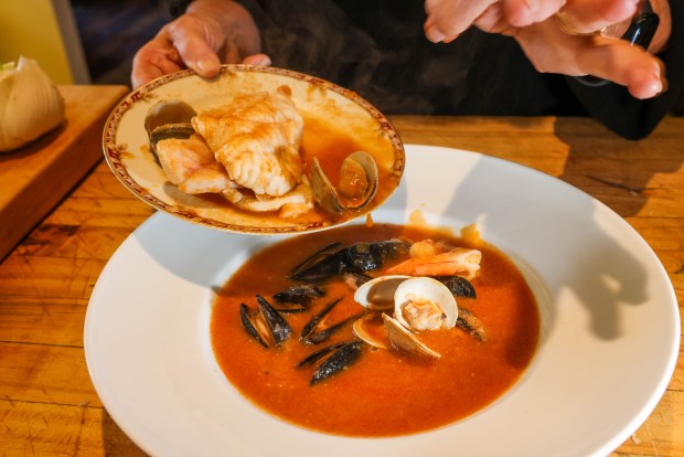 Georgeanne Brennan adds seafood such as fish, clams, mussels, and shrimp to soupe de poisson, a French seafood dish, creating her West Coast Bouillabaisse at her home in Winters, Calif., on Friday, Nov. 21, 2025. The soup features fish fumet and is made with onions, leeks, peppercorns, potatoes, fresh fish, fennel, tomatoes, and other aromatic ingredients. (Ray Chavez/Bay Area News Group)