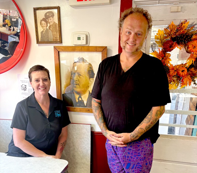 Alicia Kennedy and Charly Murphy, co-owners of Bob Hamburg since 2021, pose near a portrait of Walter Ridge who owned the restaurant for nearly six decades. Ridge went by "Bob" after purchasing the eatery from "the original Bob" Holbrook in 1933.