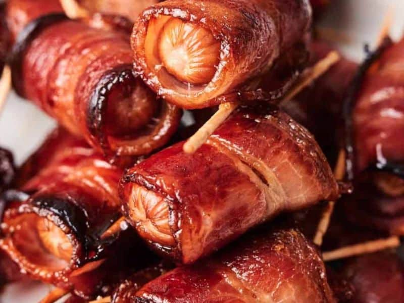 A close-up of Bacon Wrapped Sugar Smokies, held together with toothpicks and cooked to a crispy finish.