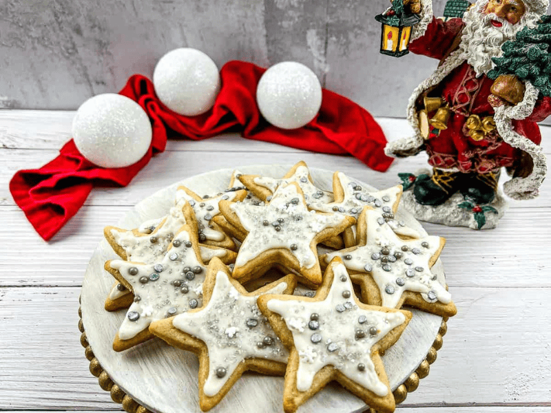 Eggnog sugar cookies on a plate with santa claus figurines.