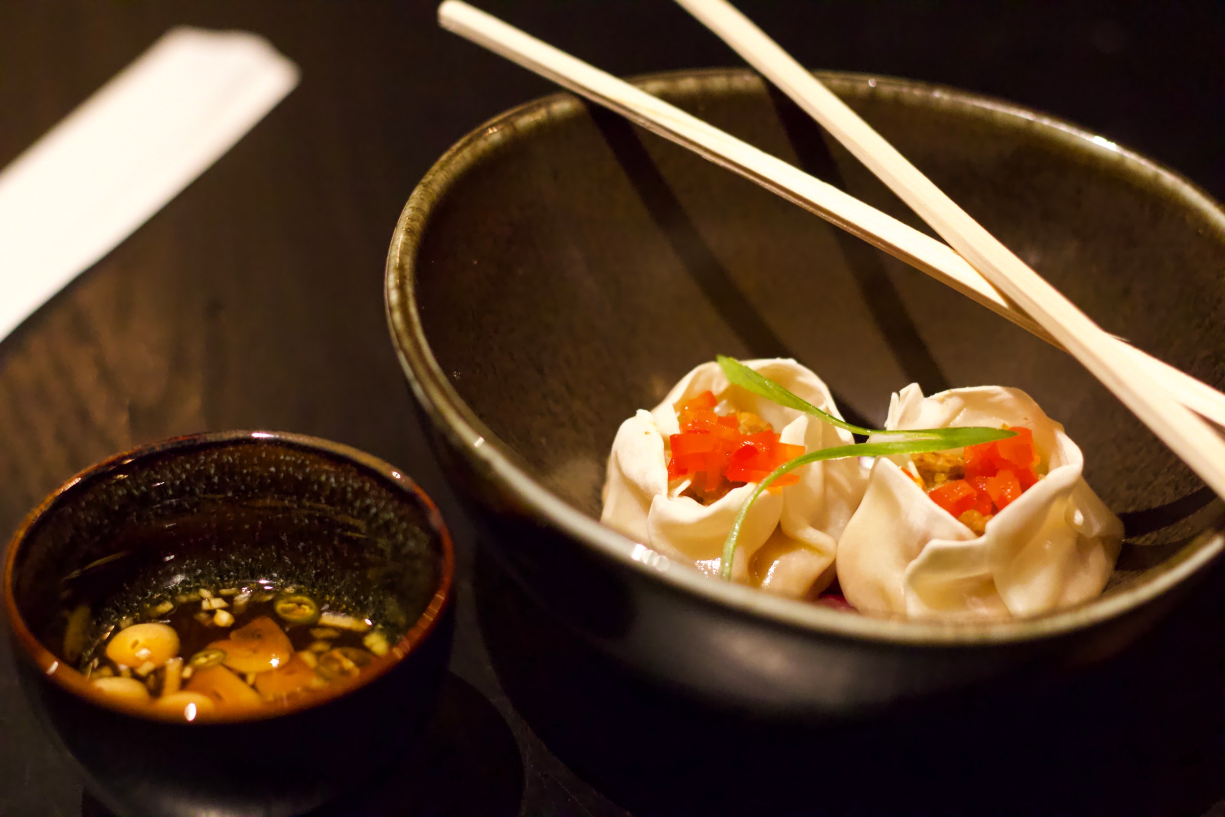 Snapper escovitch garnished with pickled peppers wrapped in two dumplings next to a soy chili dipping sauce from Bread and Butterfly in Atlanta. 