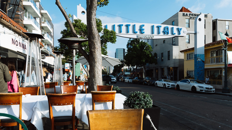 Outdoor dining on the street beneath Little Italy sign