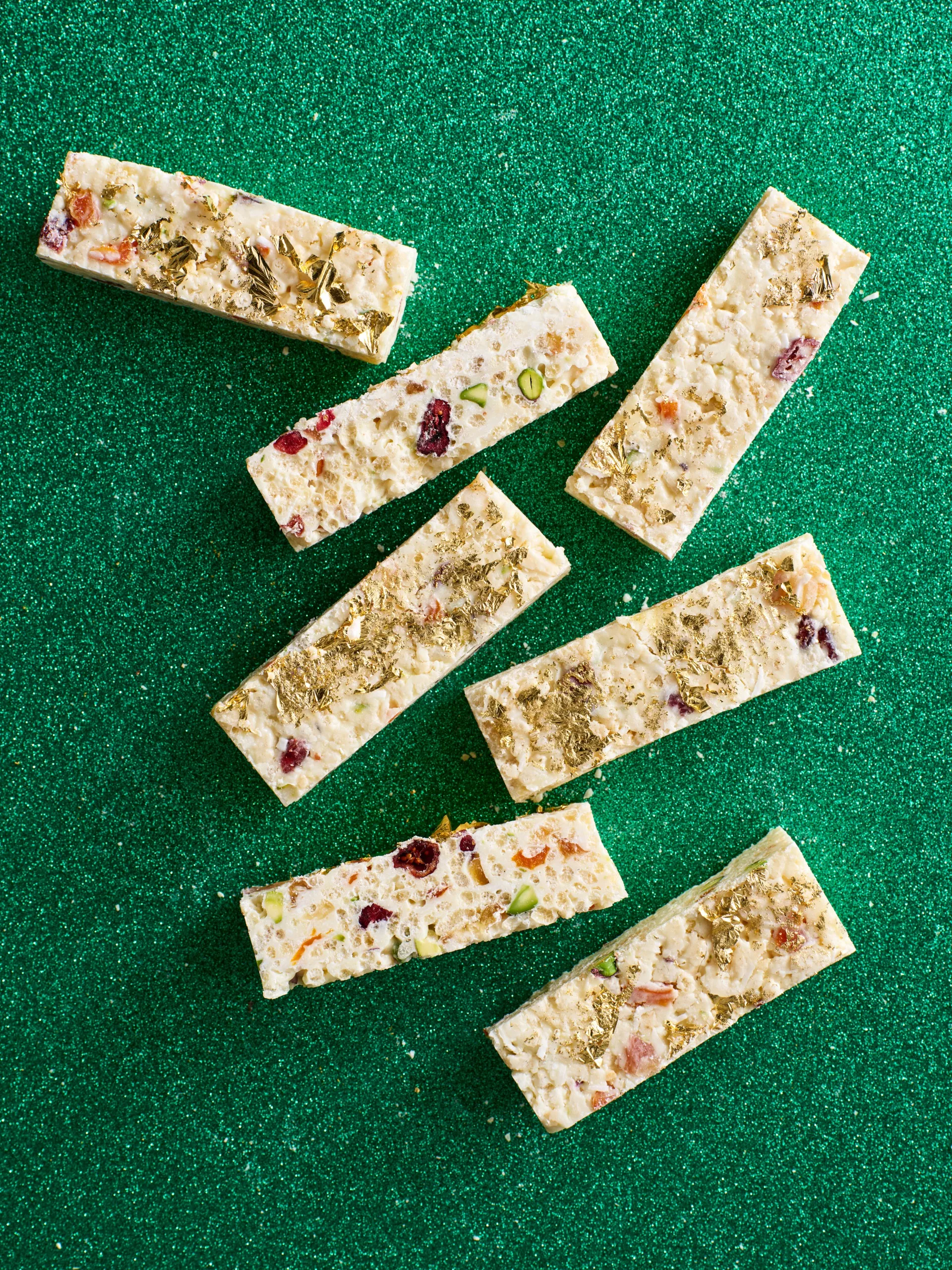 White christmas cut into small rectangular pieces with gold leaf on top and green sparkly background