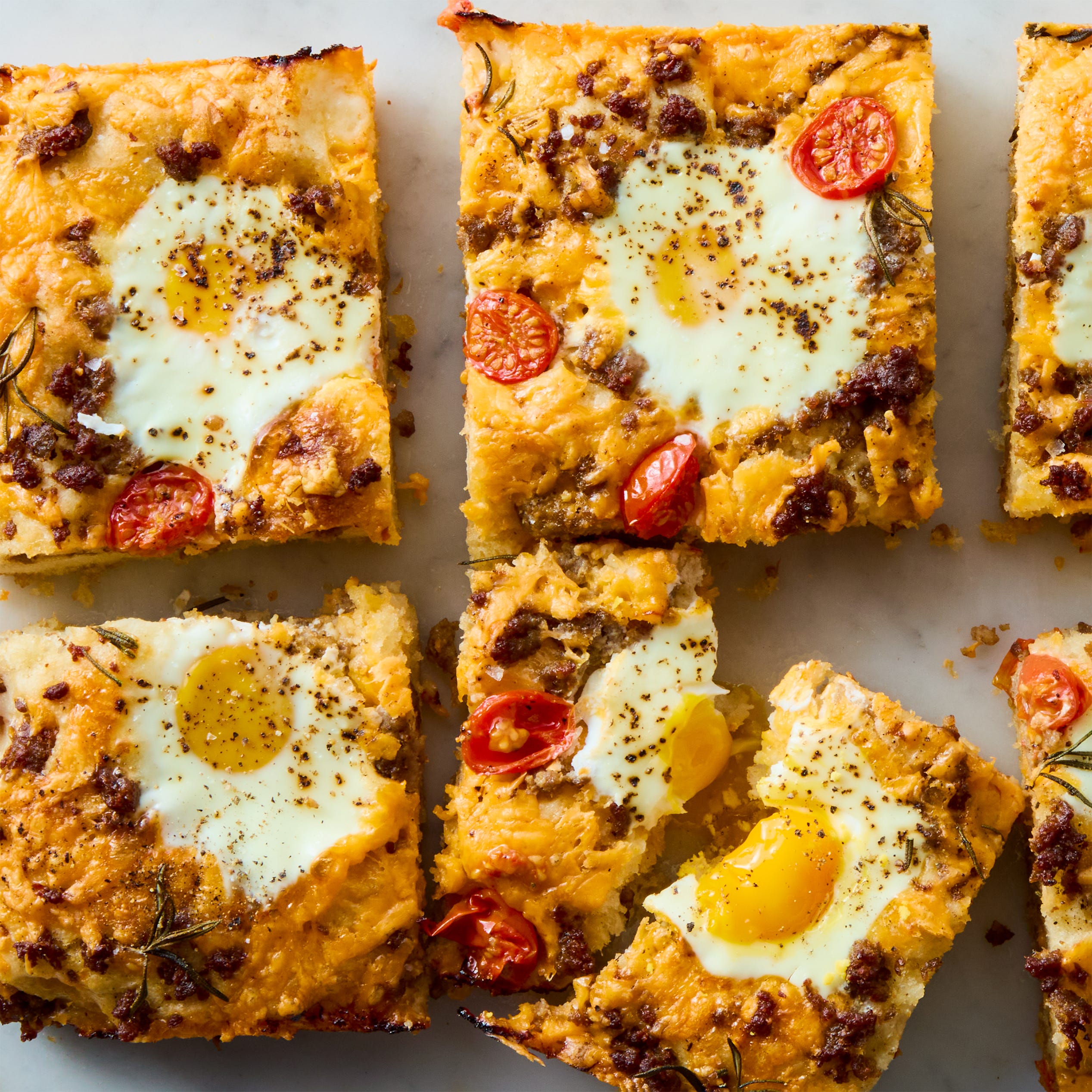 classic focaccia reimagined into the ultimate breakfast with crispy edges, layers of crumbled breakfast sausage, shredded cheese, and juicy cherry tomato and jammy eggs.