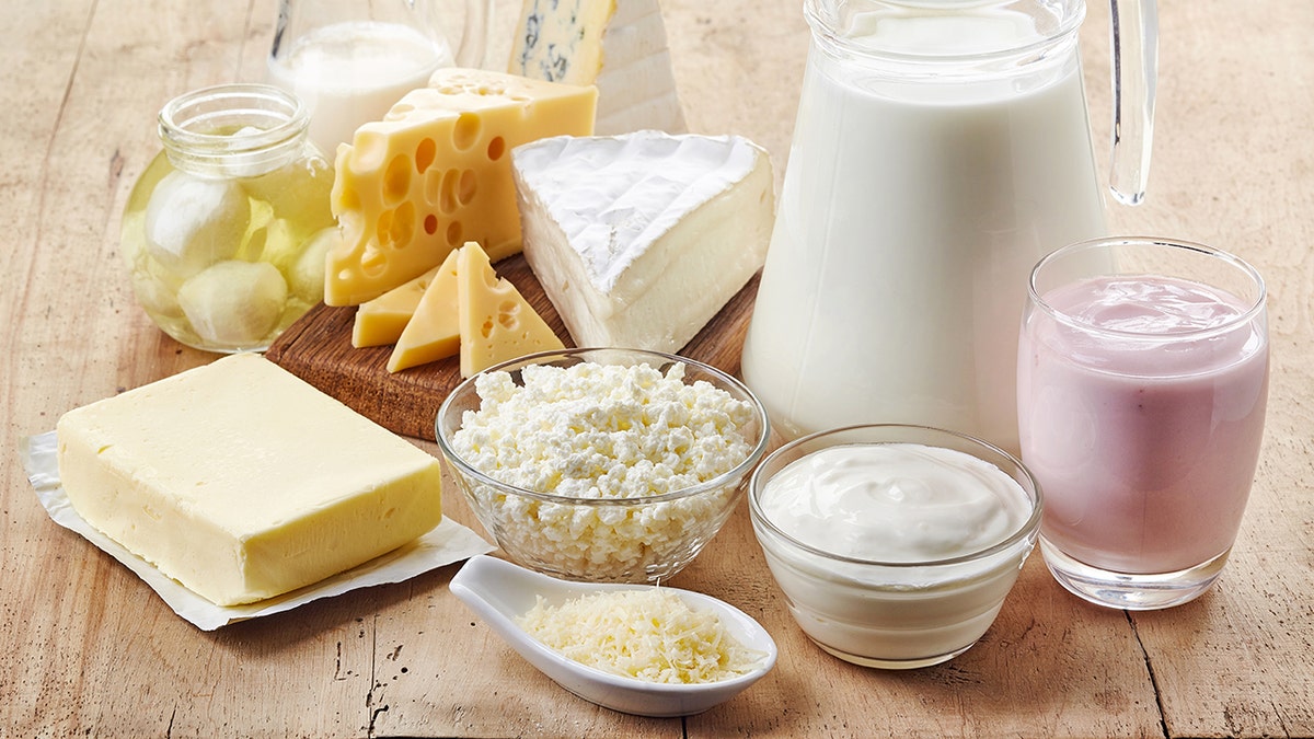 Various fresh dairy products including cheese, milk and yogurt on wooden background