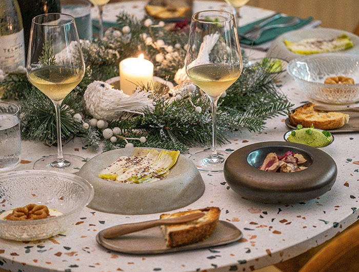 Festive Christmas dinner table setting with wine glasses and holiday greenery, town on alert after fatal Italian meal incident.