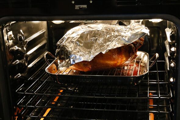 A part-covered turkey browning in the oven A part-covered turkey browning in the oven
