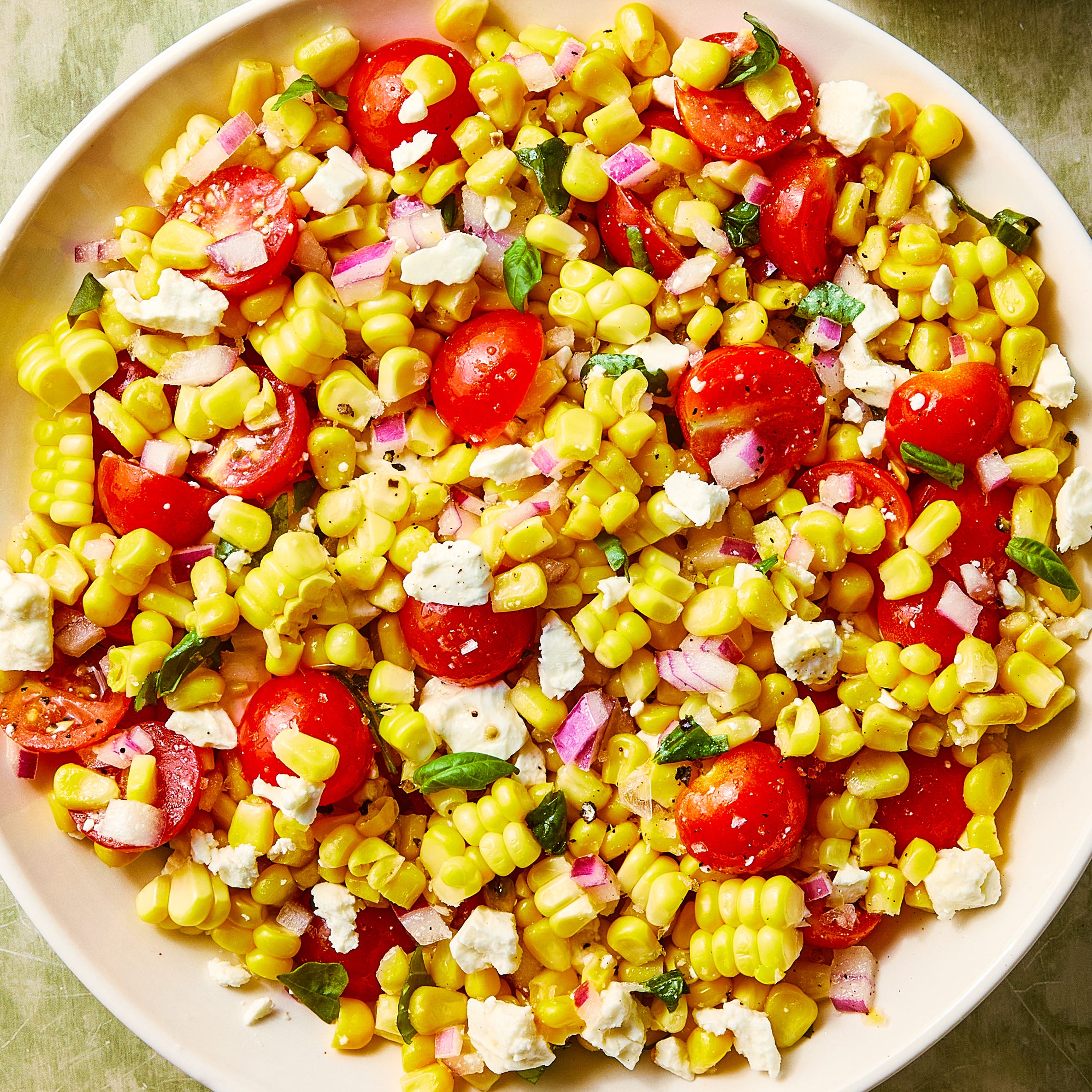 corn, chopped tomatoes, feta and basil in a bowl