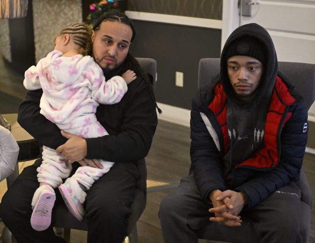 John Hernández, left, holds his daughter, Luna, 2, as Hernández and E.J. López, right, talk about the fire that destroyed their home in Zion, Dec. 27, 2025. (Michael Schmidt/for the Chicago Tribune)