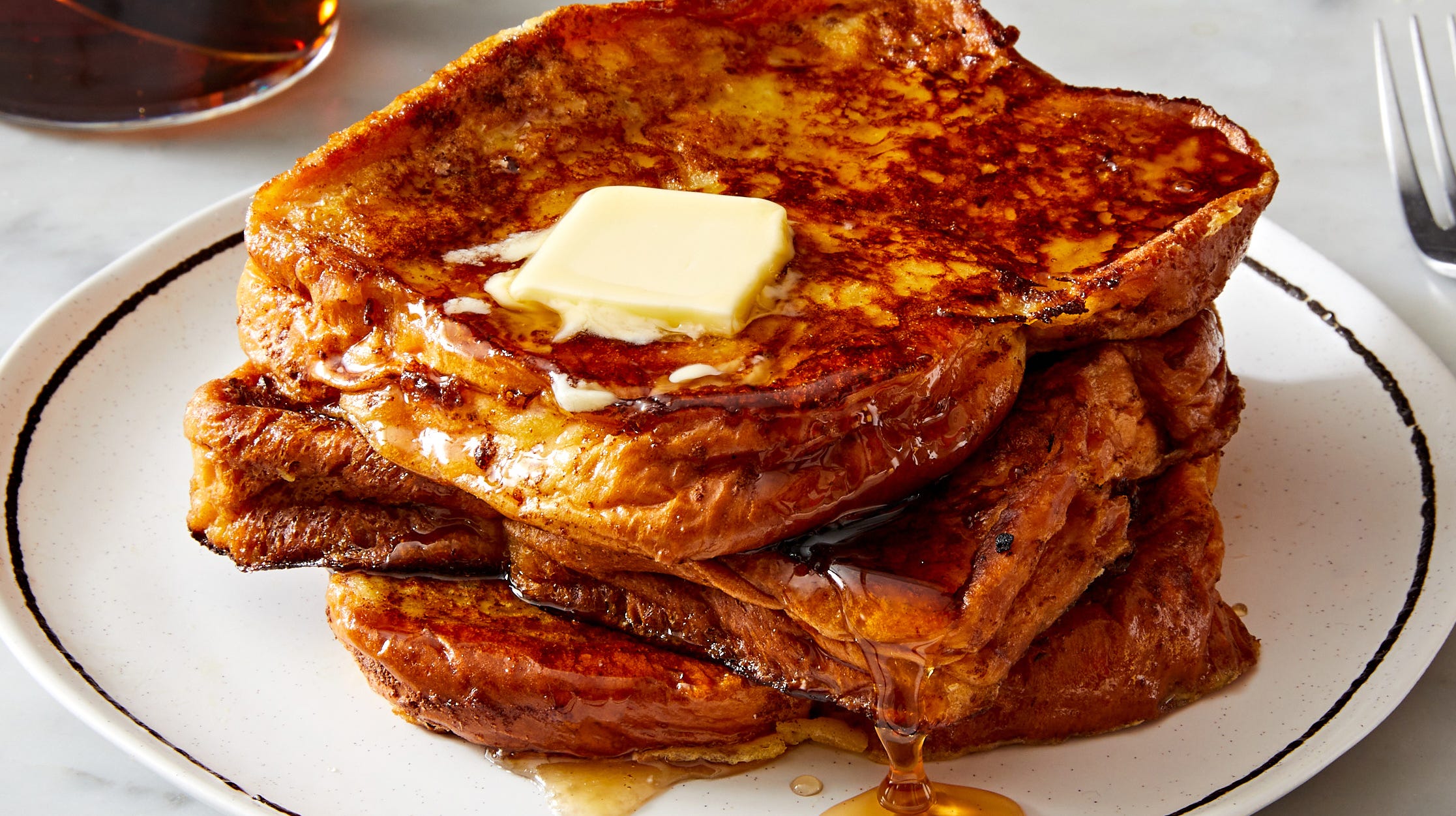 French Toast a stack of french toast on a white plate topped with butter and maple syrup