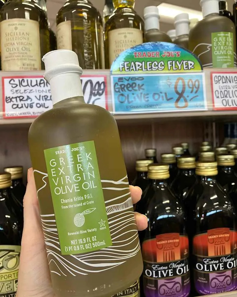 Someone holding bottle of Trader Joe's Greek Extra Virgin Olive Oil.