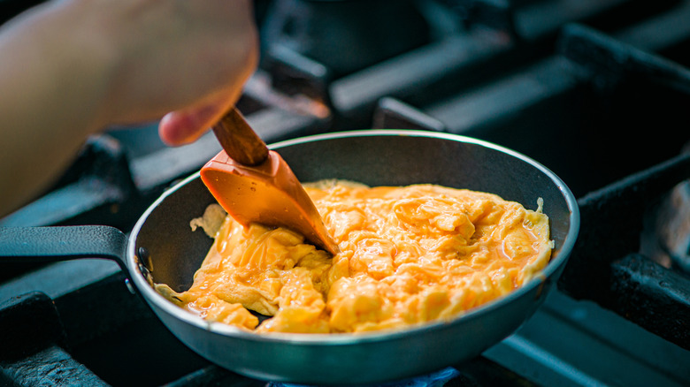 A person cooking scrambled eggs