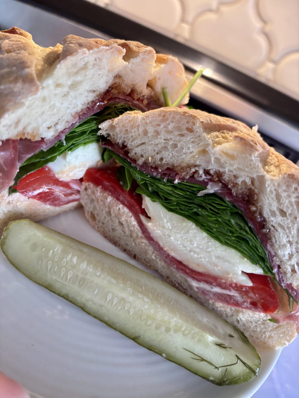 Mayo, cracked black pepper, roasted red pepper, oregano, salt, mozzarella, spinach, oil, vinegar, prosciutto, fig spread and a grillo pickle on the side.