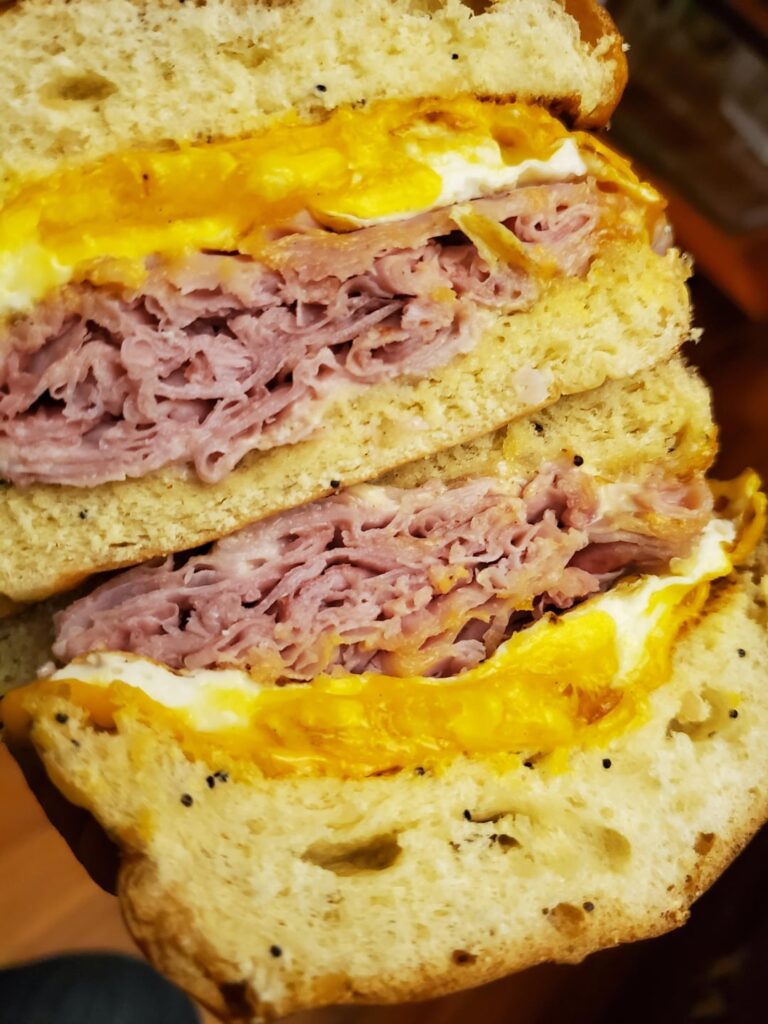 Making breakfast sandwiches for tomorrow to save some money . Egg ham cheese on soft onion roll.