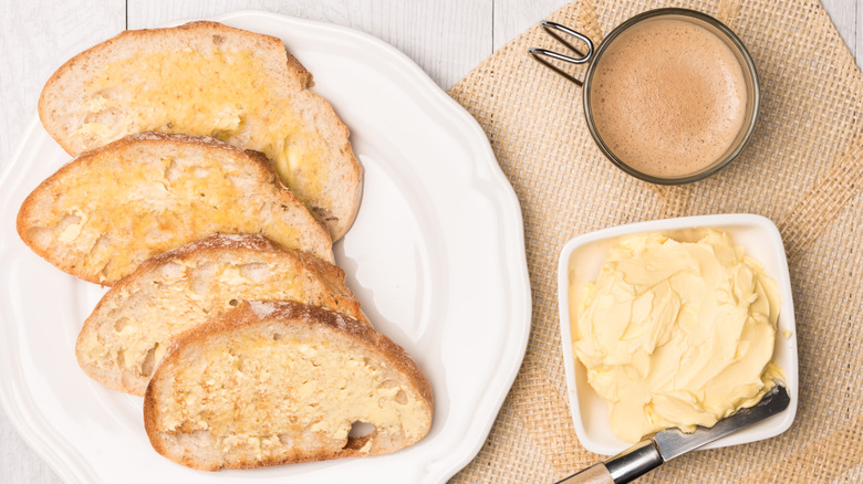 Toast, coffee, and butter on a table with a burlap napkin.