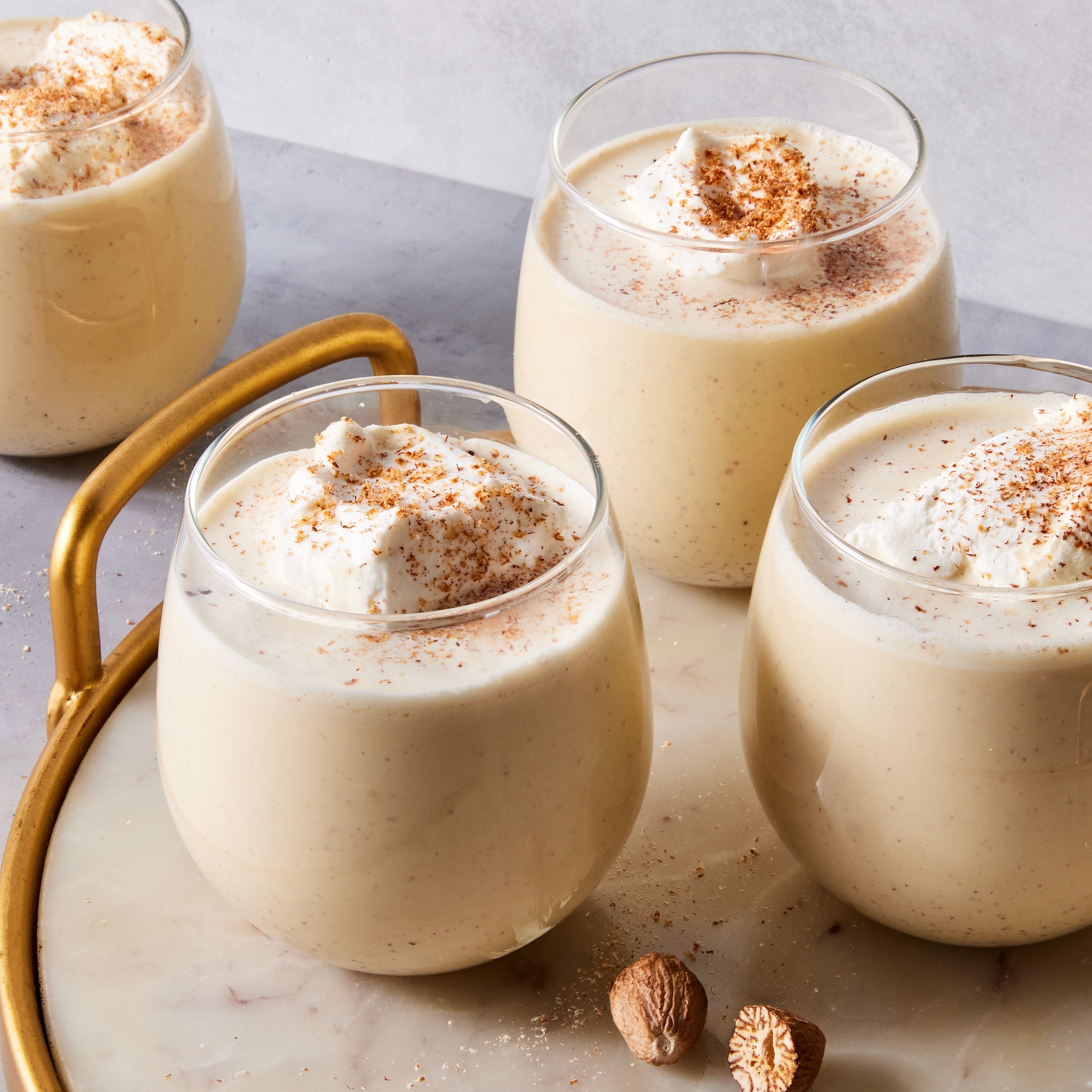 homemade eggnog topped with whipped cream and grated nutmeg