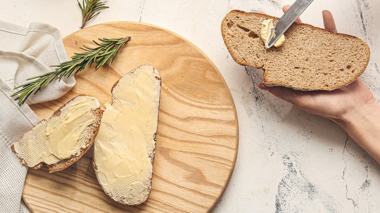 Hands spreading butter on bread