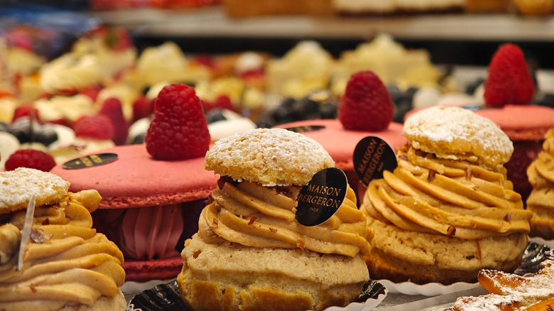 Pastries topped with cream and red fruit in a bakery window