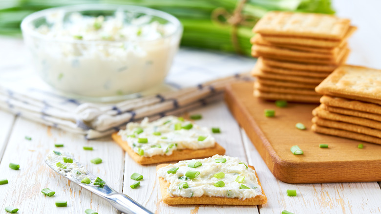Crackers spread with soft cheese and chopped chives
