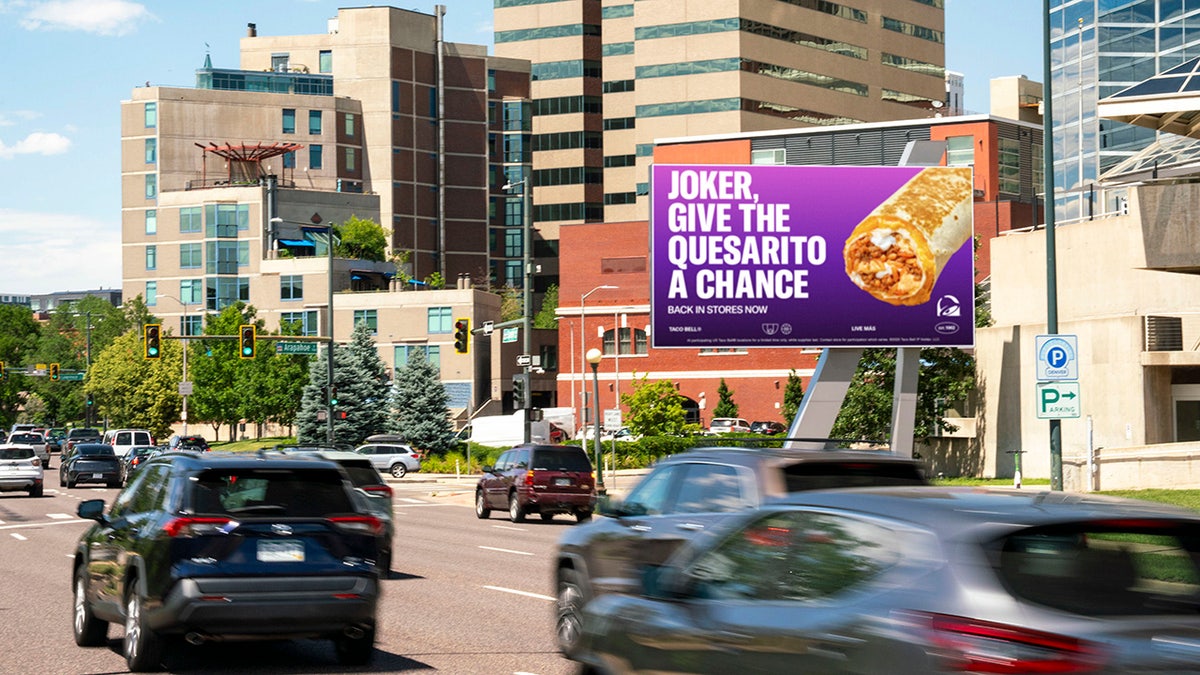 Billboard seen above roadway calling for NBA star Jokic to try the Taco Bell Quesarito.