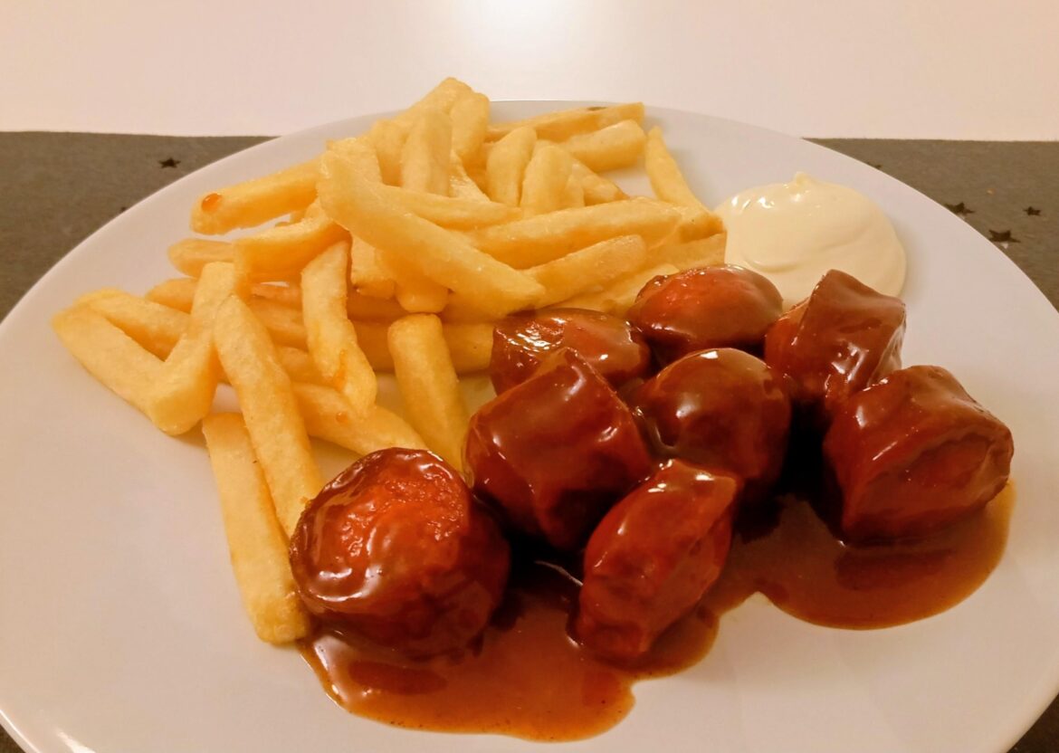 Currywurst Pommes (sausage in curry sauce and fries). German fastfood