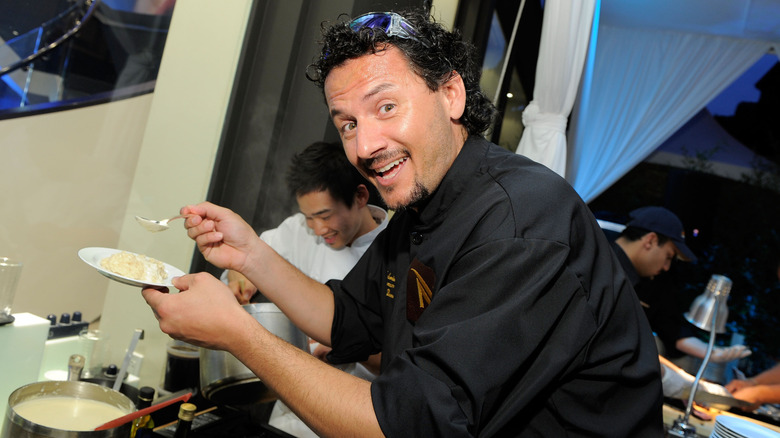 Fabrizio Carro spoons gnocchi onto a small plate with chefs with chefs in the background