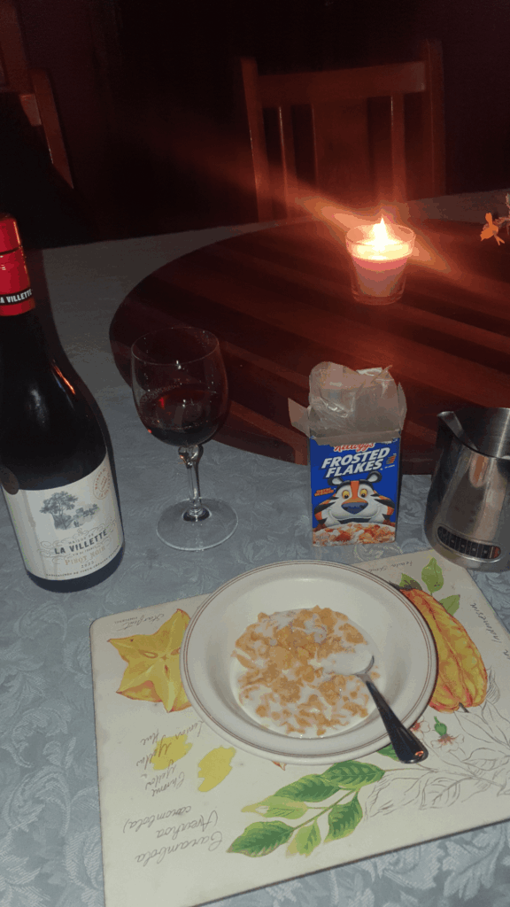 Candle lit Christmas dinner for one, Frosted Flakes and a bottle of Pinot Noir