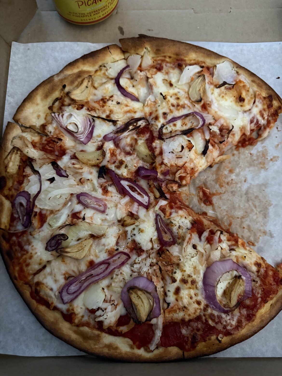 Pizza with red onions, white onions, and whole cloves of garlic.