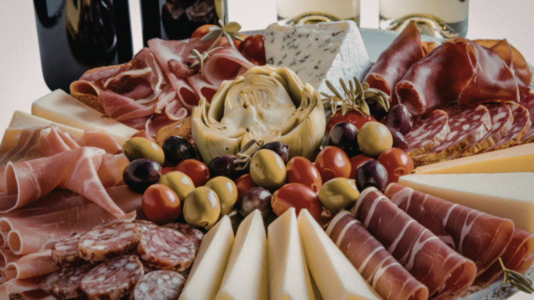 An Italian antipasto platter with cold cuts, cheese, olives, and an artichoke
