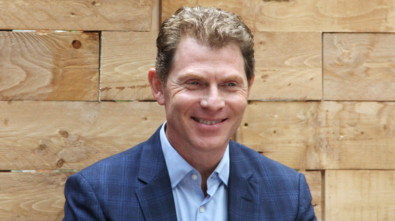 Bobby Flay smiling against wooden backdrop