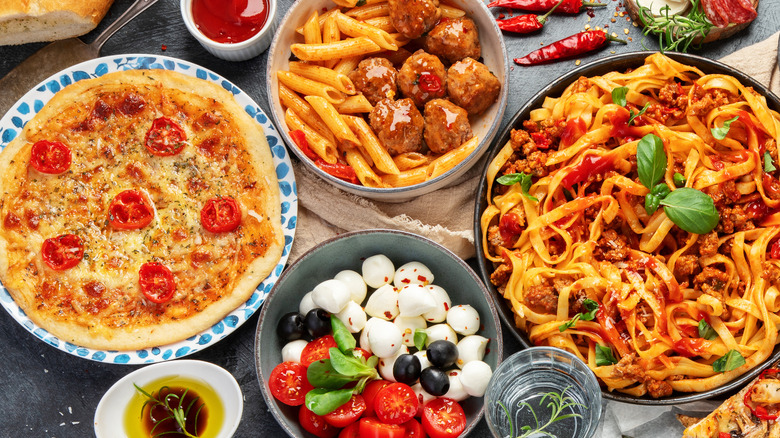 italian pasta, meatballs, and pizza on a table