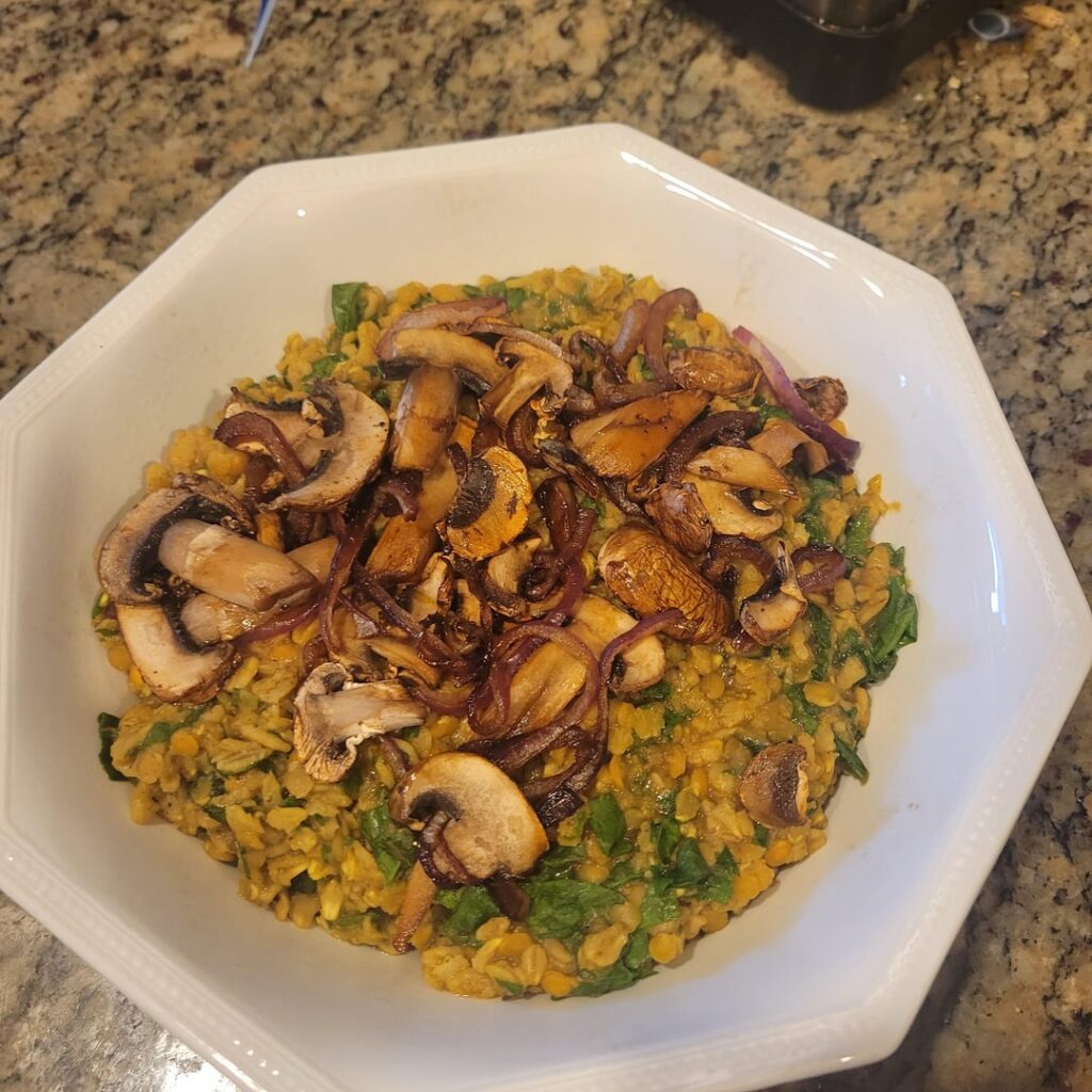 Savory oats with red lentils and diced spinach, garnished with mushrooms and red onion