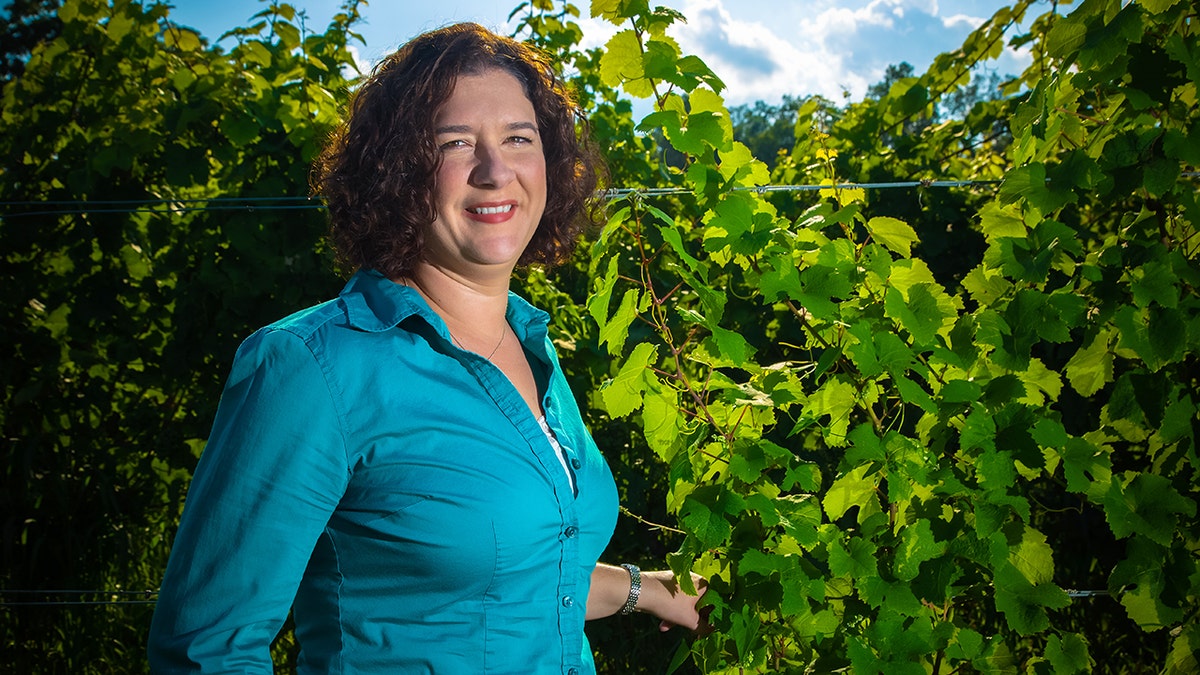 Nova Cadamatre wears a blue shirt in a vineyard.