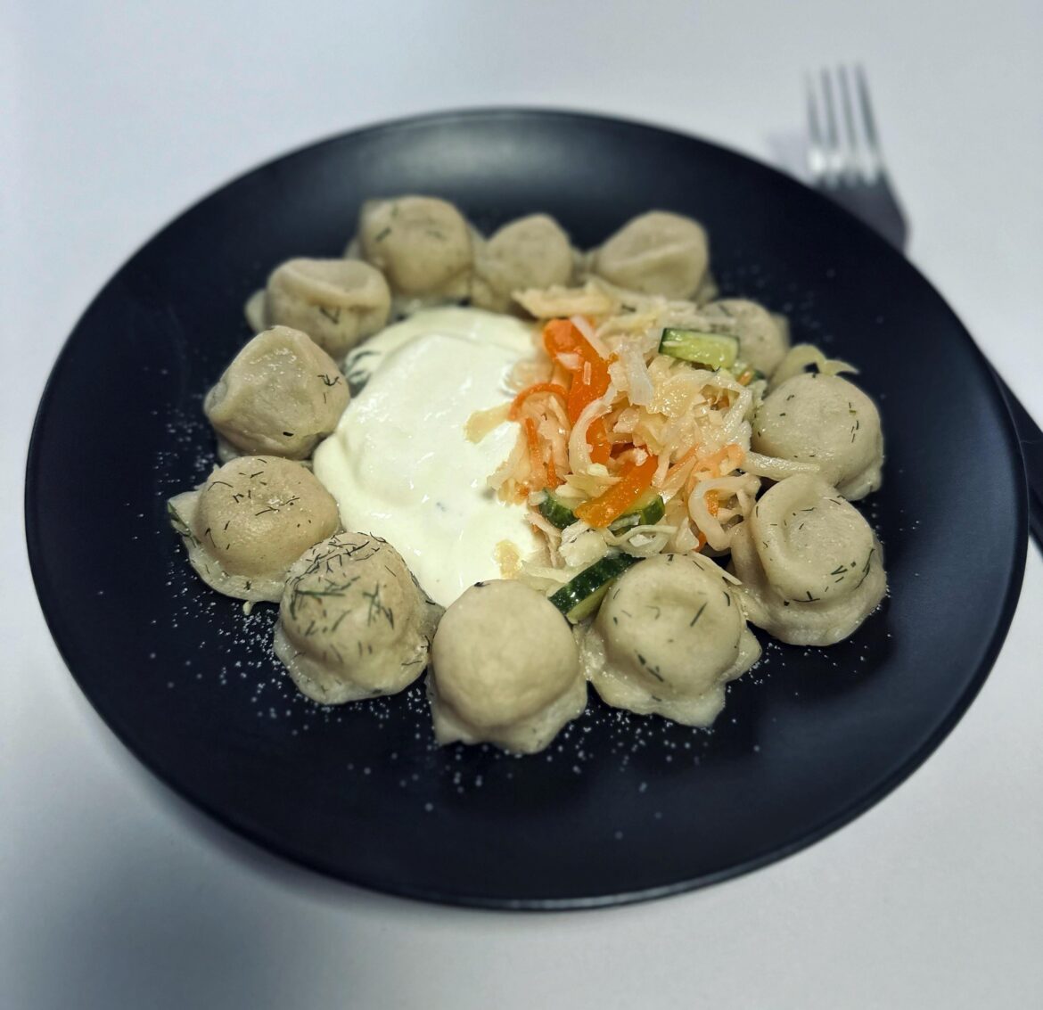 Handmade boiled pelmenis with sour cream and salad