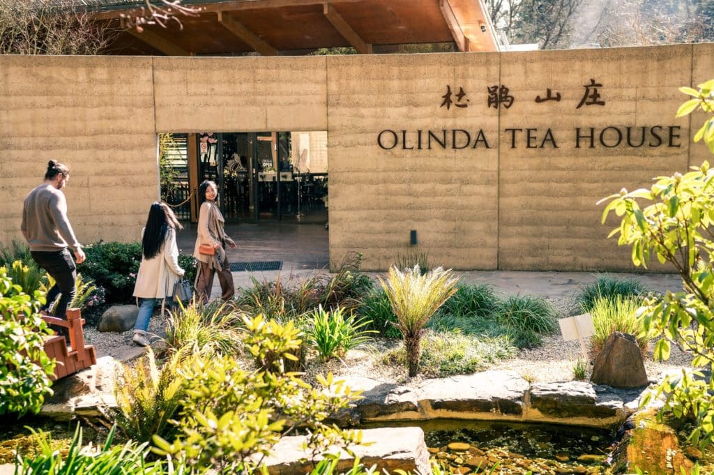 people walking past a garden and into Olinda Tea House