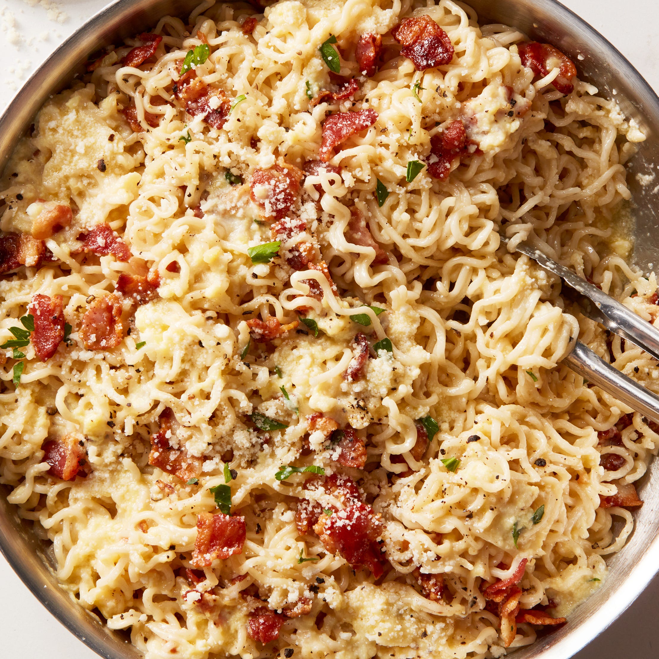 ramen noodles with bacon and creamy carbonara sauce topped with parmesan cheese