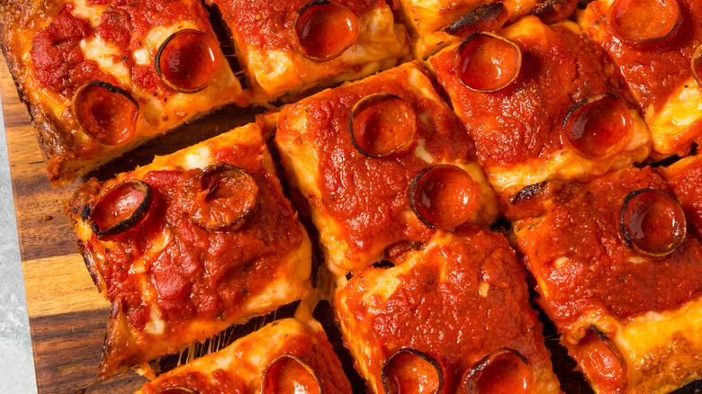 Homemade Detroit-style pizza with crispy pepperoni on wooden cutting board