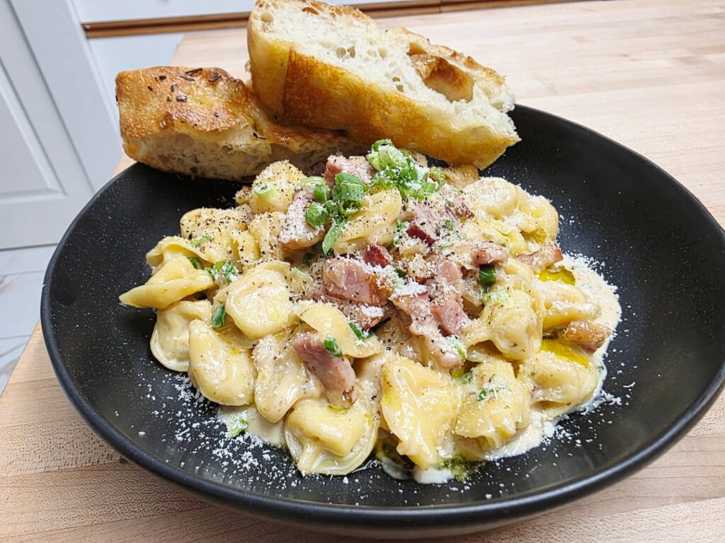 Four cheese cappeletti in bacon cream sauce with green onions
