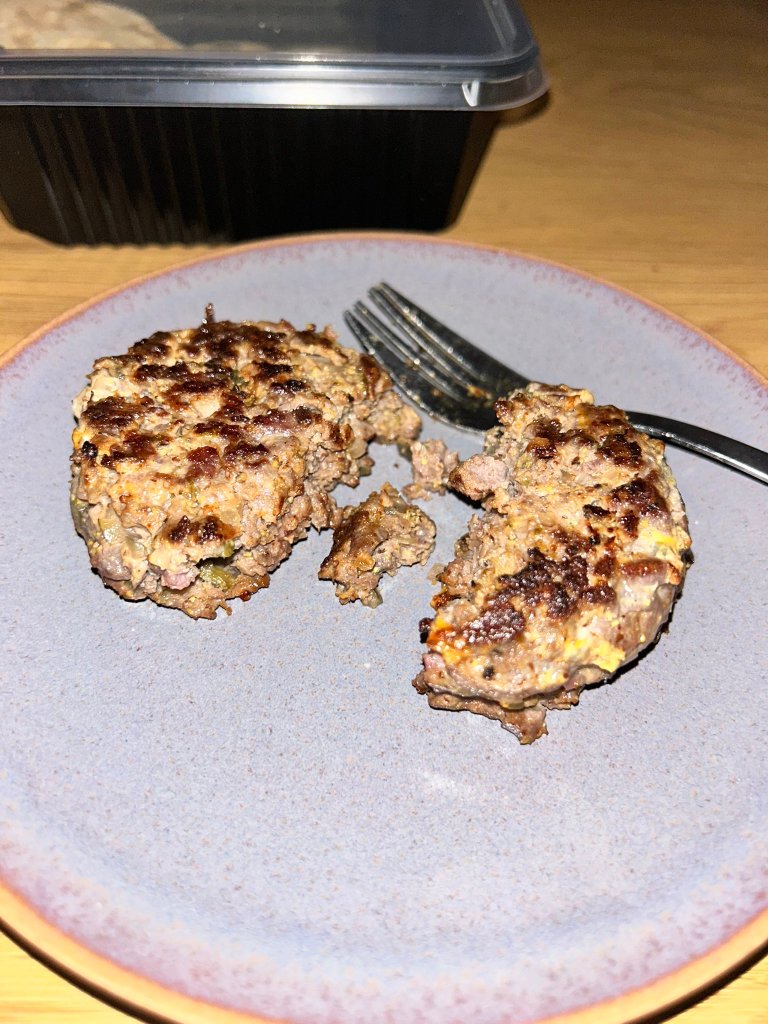 Steak tartare, which has been cooked and broken into pieces, on a gray plate with a fork.